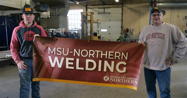 Chuck Terry proudly displays one of his welding banners